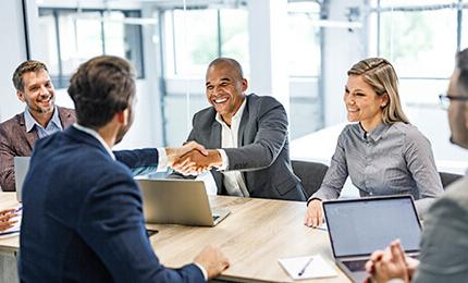 Two men shake hands at a team meeting